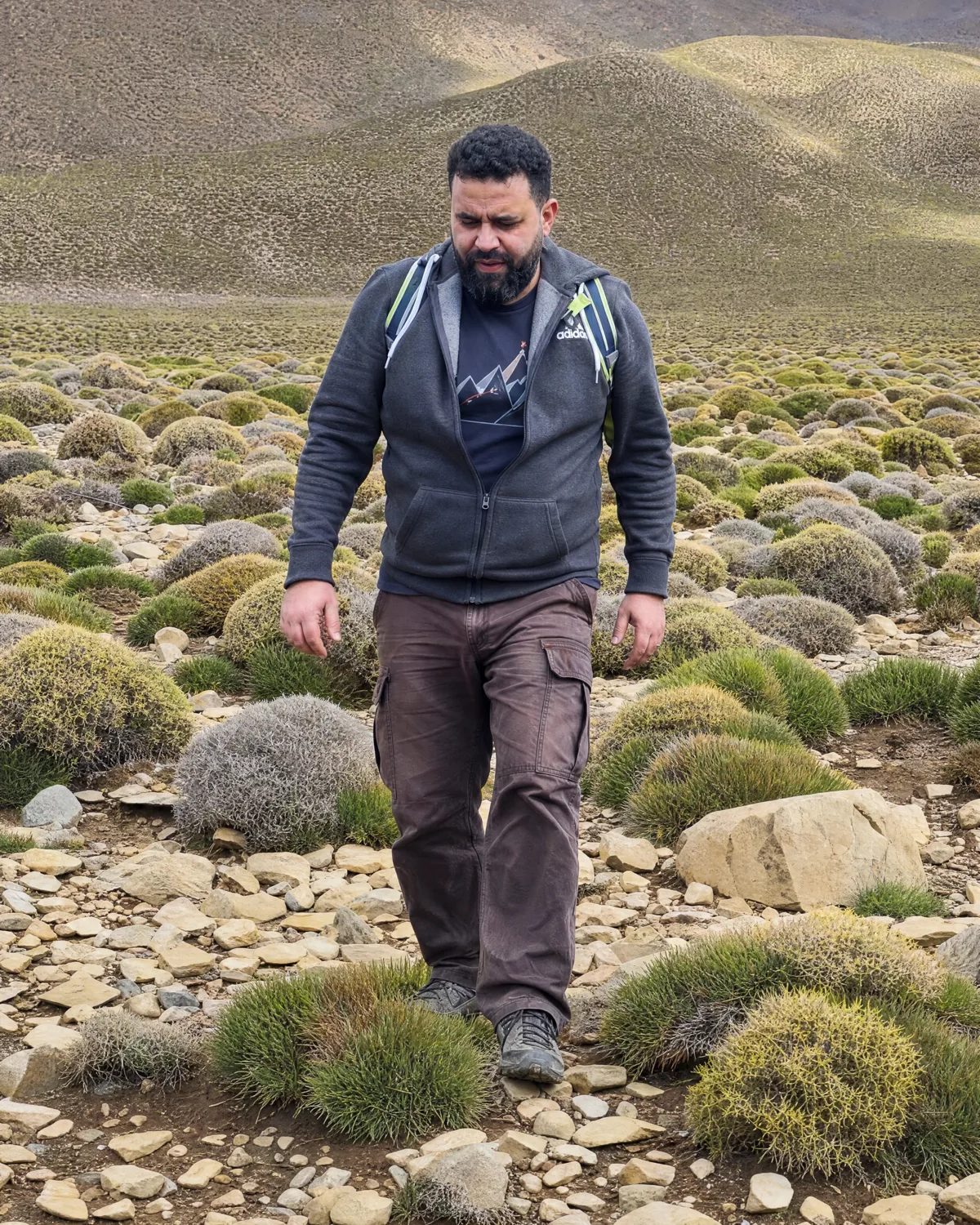 Abdelhay Fadil geht mit Rucksack durch eine karge Berglandschaft