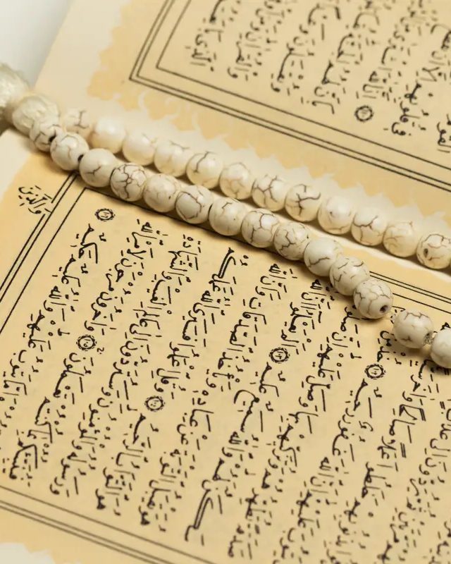Aufgeschlagener Koran, darauf eine helle Gebetskette